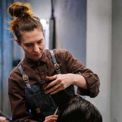 A woman styling a customer's hair at a modern salon, showcasing professional hair care services.